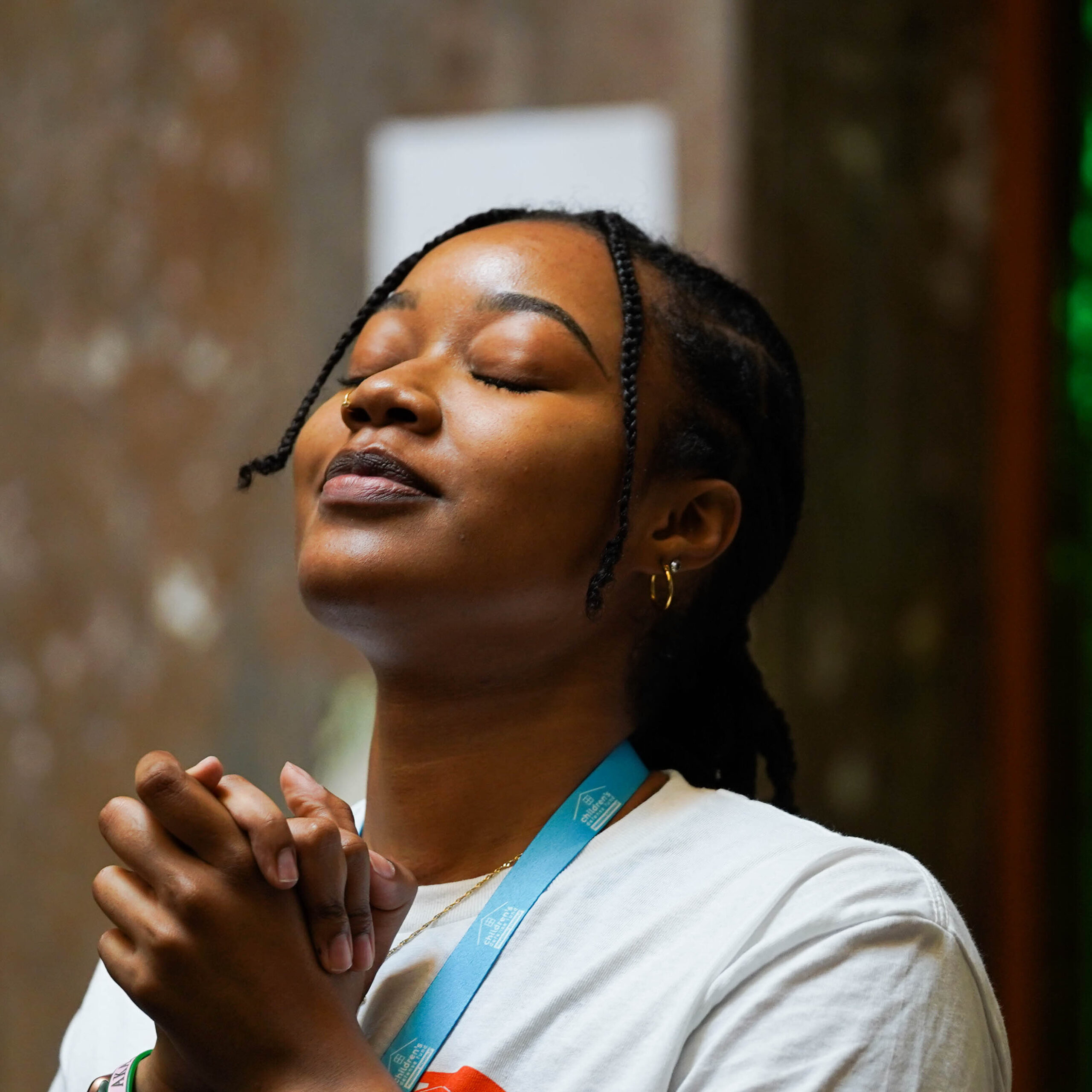 Young woman claps her hands together and looks up to the sky in peace